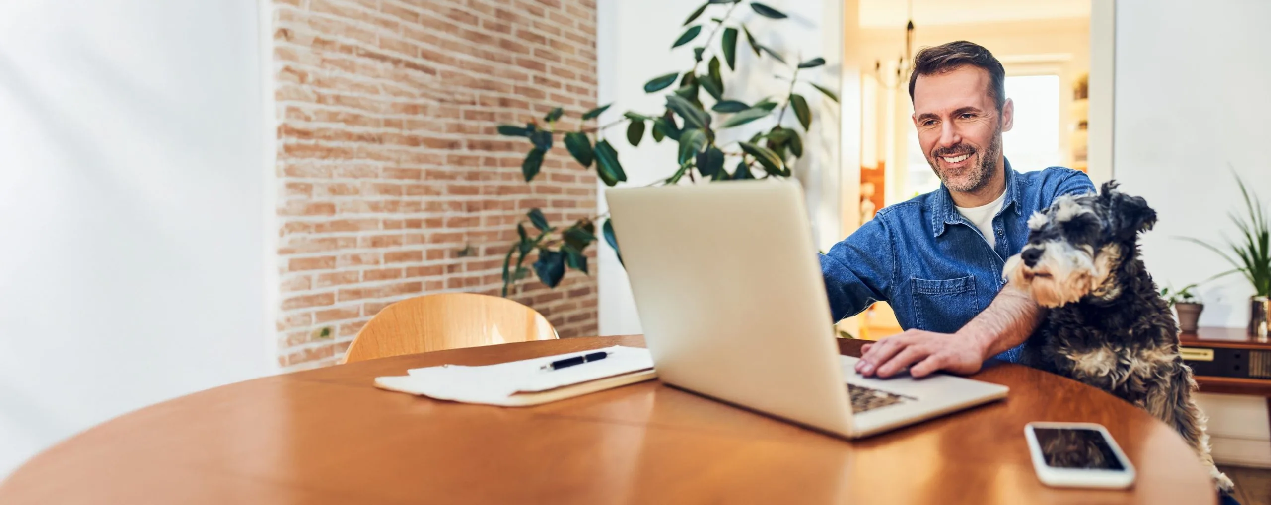 Man checking his debt consolidation loan rate online on a laptop with his dog beside him