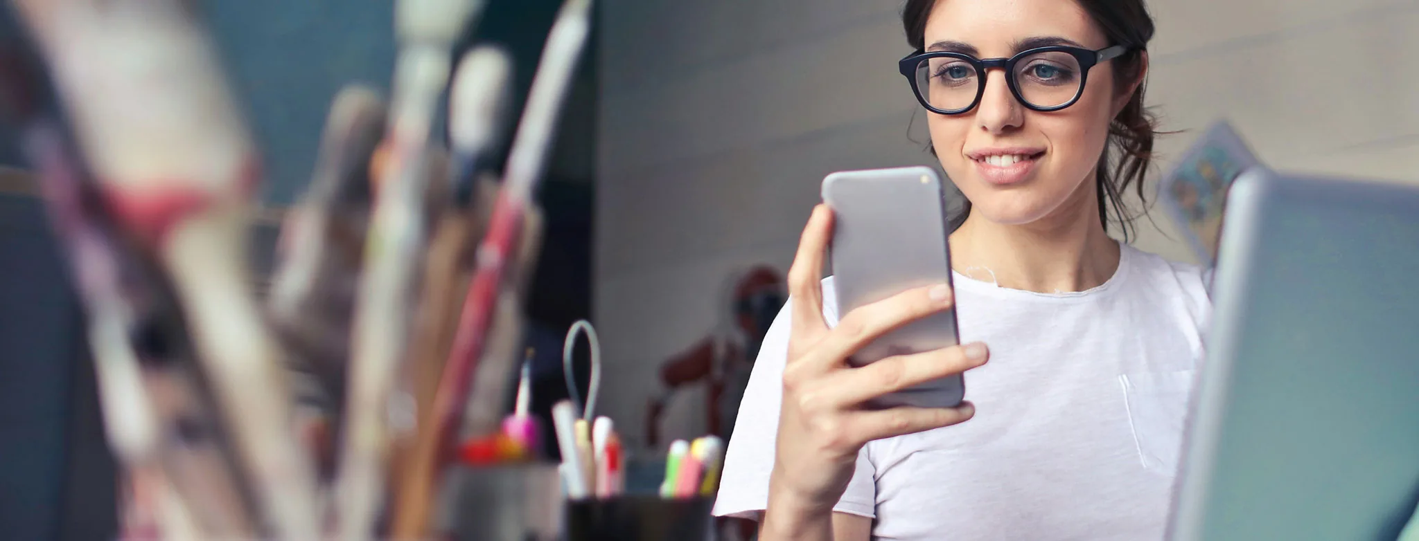 Woman using her smartphone to check her online loan rate at her workspace