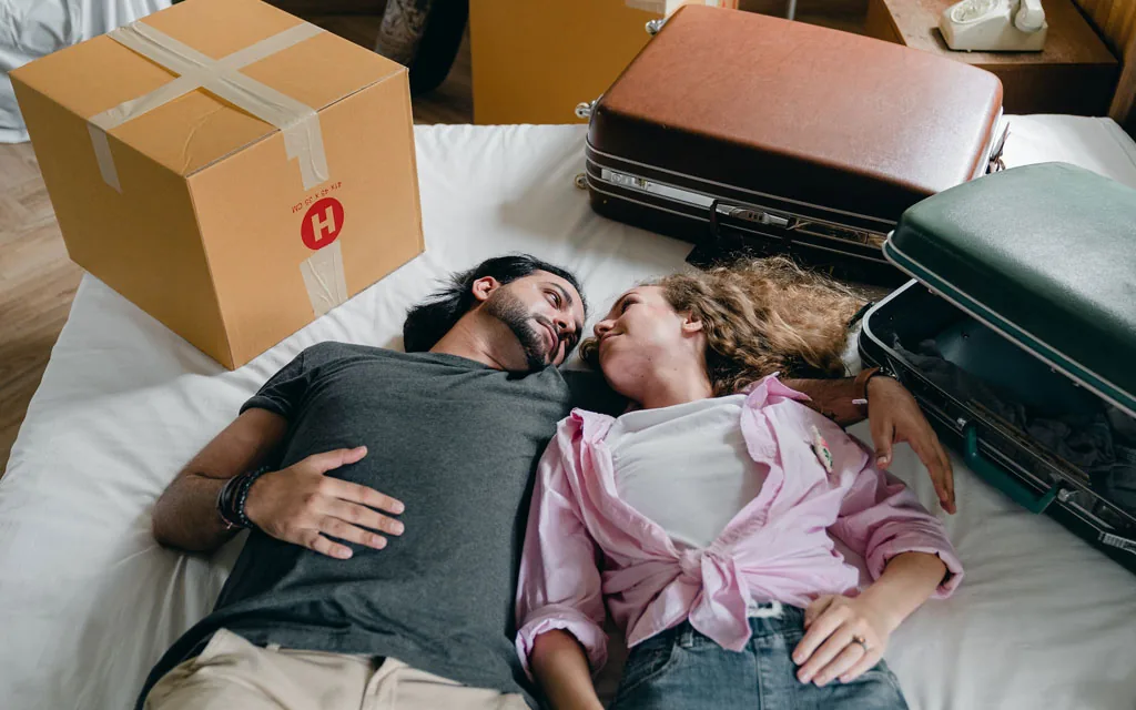 Couple relaxing among moving boxes and luggage, representing a personal loan for a major purchase